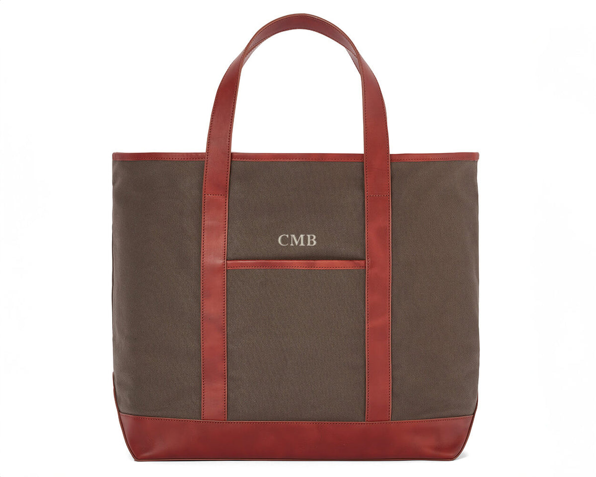 The Travis Tote Bag Cotton Twill: Scotch Green - Rye Embroidery, features a brown canvas with leather trim, monogrammed CMB above a front pocket.