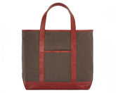 The Travis Tote Bag Cotton Twill features brown canvas with red leather trim, long handles, a front pocket, and CMB initials embroidered.