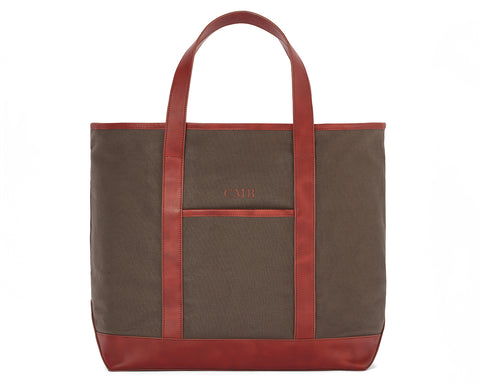 The Travis Tote Bag Cotton Twill features brown canvas with red leather trim, long handles, a front pocket, and CMB initials embroidered.