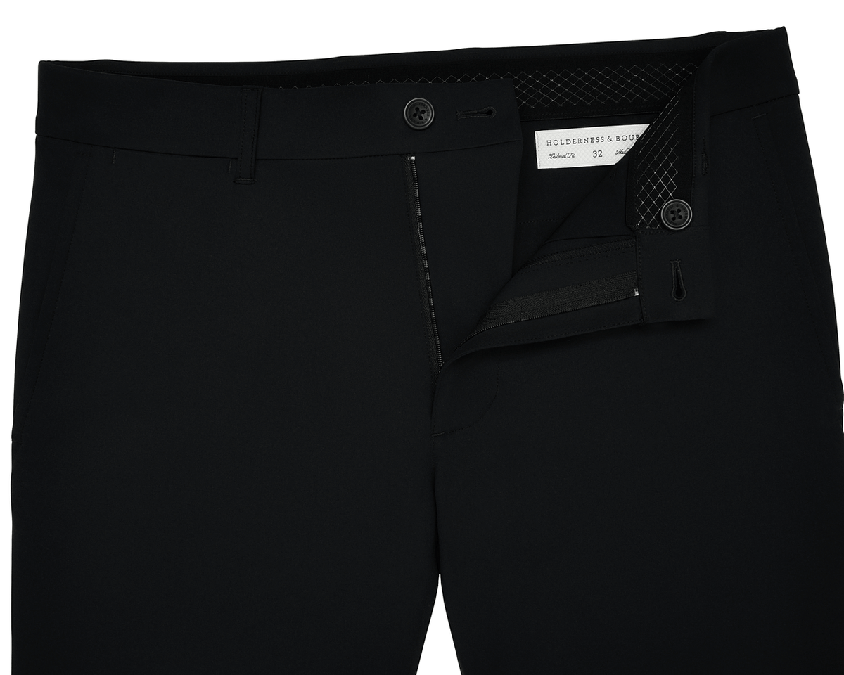 The Harwood Short: Black, displayed with a partly open zipper and undone button, revealing a Holderness & Bourne label and size 32 inside the waistband.