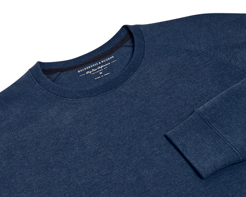 The Kennedy Crewneck: Heathered Atlantic, a navy-blue sweatshirt with a ribbed cuff, showcasing a tailored fit and performance design with a plush terry interior.