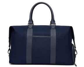 The Byers Duffel Bag: Navy Ballistic, featuring sturdy fabric, leather handles, vertical front straps, and a zippered side pocket, ideal for travel with easy-access top opening.