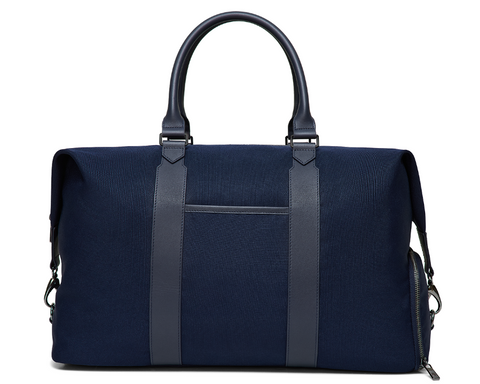 The Byers Duffel Bag: Navy Ballistic, featuring sturdy fabric, leather handles, vertical front straps, and a zippered side pocket, ideal for travel with easy-access top opening.