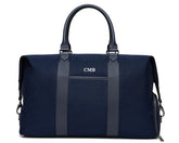 The Byers Duffel Bag: Navy Ballistic - White Embroidery, featuring leather accents, front and side pockets, personalized initials “CMB”, and a wide top opening for easy access.
