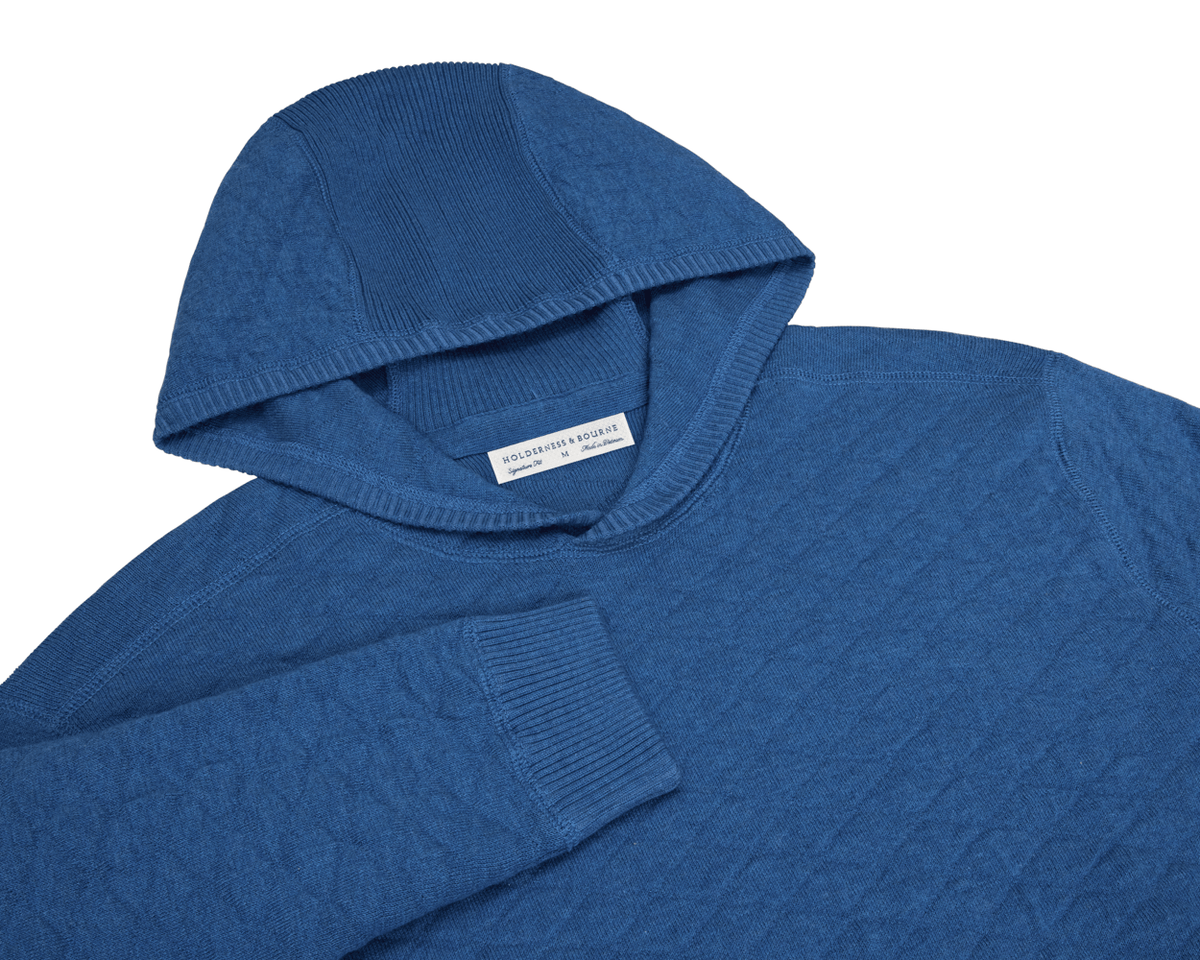 The Wallace Hoodie Sweater in heathered Maidstone blue, featuring ribbed hood lining, cuffs, and side panels, made from 100% Egyptian cotton.