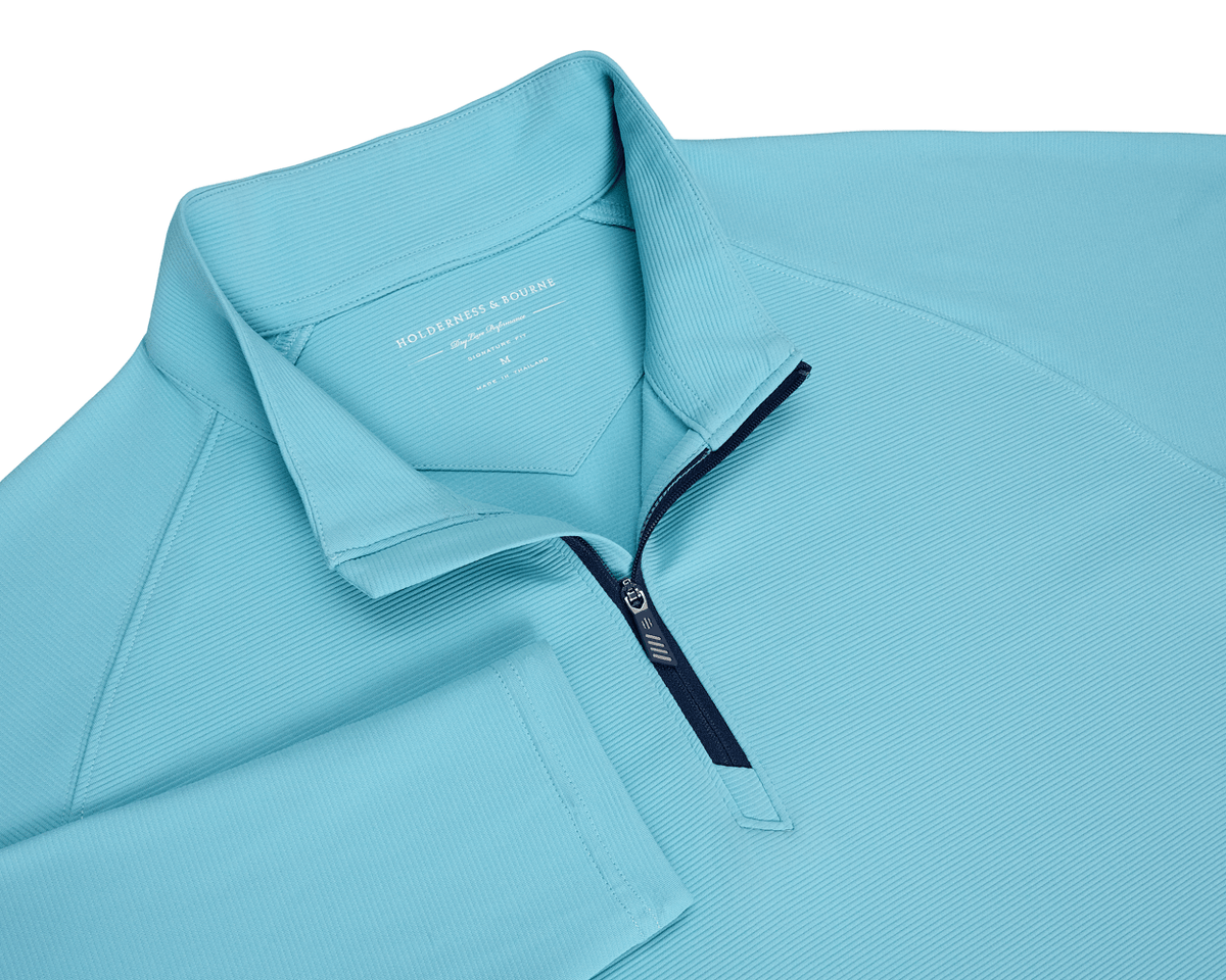 The Stuart Quarter-Zip: Harbor features a ribbed-texture, long-sleeve design with a navy zipper and standing collar, showcasing Holderness & Bourne branding inside the neck.