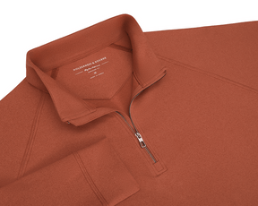 The Westland Quarter-Zip: Heathered Russet features a stand-up collar, raglan seams, and gunmetal zipper, offering moisture-wicking performance and a soft feel.