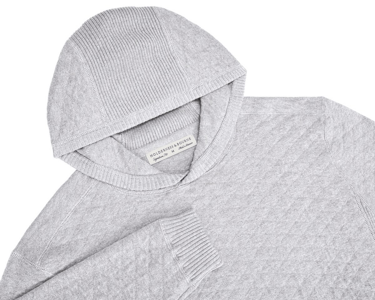 The Wallace Hoodie Sweater: Heathered Gray, features a light-gray knit with ribbed detailing, hood, and cuff, plus a “Holderness & Bourne” label at the neckline.