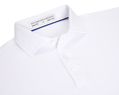The Anderson Shirt: White, short-sleeved polo with structured spread collar, three-button placket, and performance fabric for stretch and moisture wicking. Size M, made in Korea.