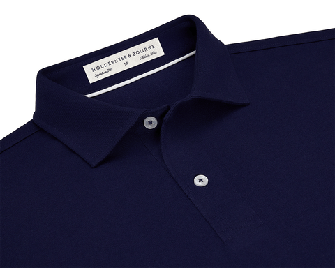 The Neville Shirt: Navy, featuring a dark navy-blue polo with a folded collar, two-button placket, and a label reading HOLDERNESS & BOURNE, Signature Fit, M, Made in Peru.