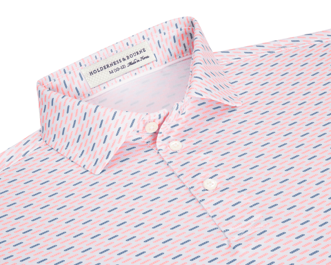 The James Boys Shirt: Cape & Andover features a light polo with coral and navy dash pattern, structured collar, and three white buttons.