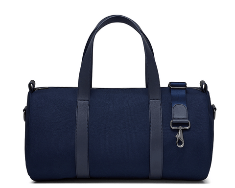 The Marston Banker Bag: Navy Ballistic, featuring top carry handles, adjustable shoulder strap, Napa leather trim, oxford stripe lining, and gunmetal hardware. Ideal for gym or travel.