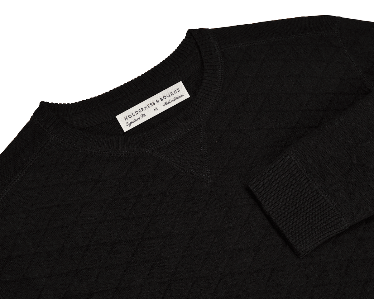 The Ward Crewneck Sweater: Black, showcases a diamond-quilted texture, crafted from soft Egyptian cotton, with a visible “HOLDERNESS & BOURNE” label inside the collar.