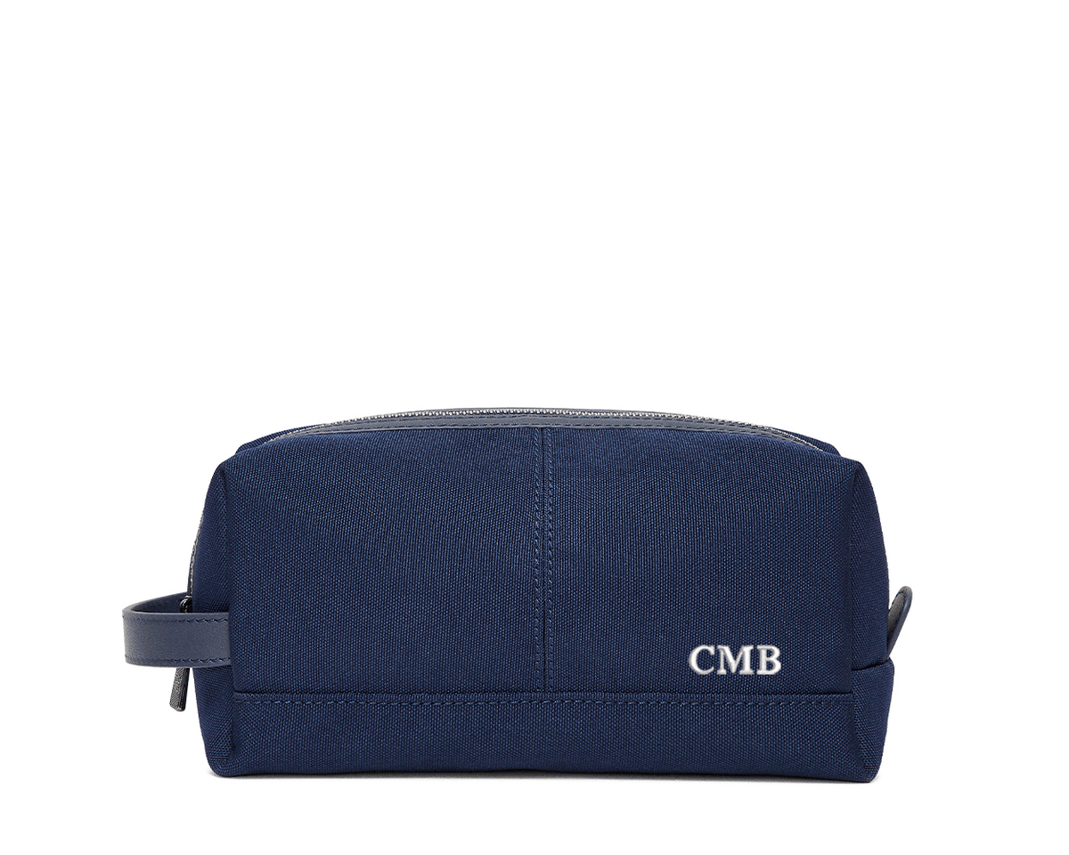 The Littler Dopp Kit: Navy Ballistic - White Embroidery, featuring a rectangular design with a top zipper, side handle, and personalized initials CMB.