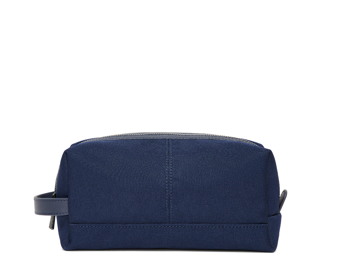 The Littler Dopp Kit: Navy Ballistic, a rectangular zippered toiletry bag with a fabric handle, features minimal stitching and a water-resistant interior pocket.