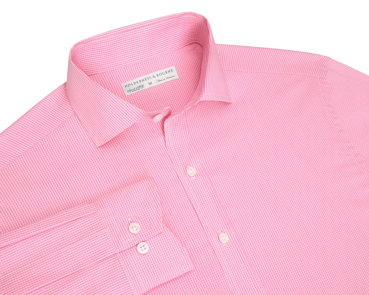 The McAllister Shirt: Belmont, a light pink micro-gingham men's dress shirt, features a structured spread collar, white buttons, and a visible cuff.