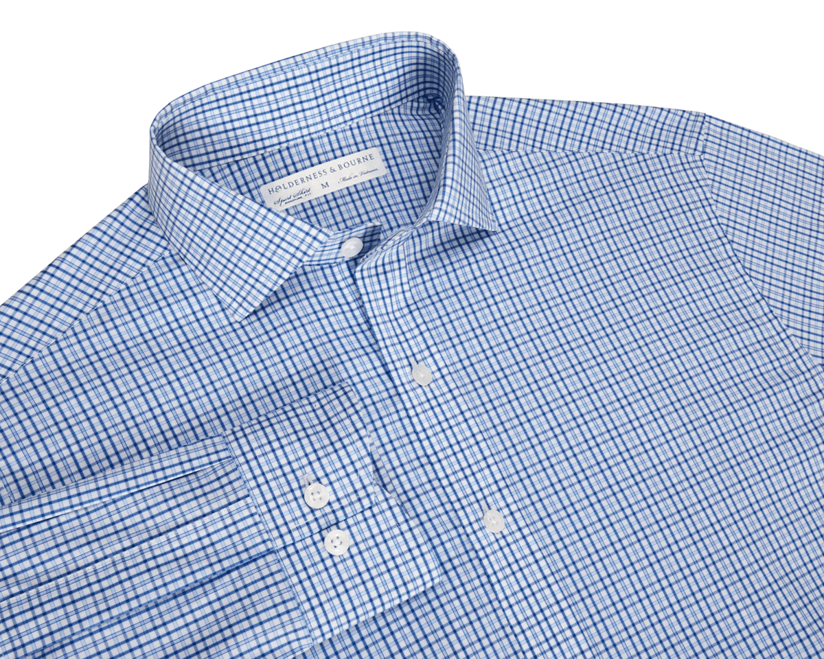 The Wright Shirt: Vista Blue, a men’s long-sleeve dress shirt with a blue windowpane pattern, spread collar, and white buttons, offers comfort and wrinkle resistance.
