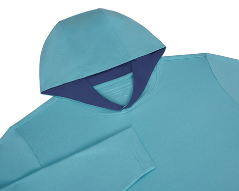The Jackson Hoodie: Harbor, a minimalist turquoise performance hoodie with navy-lined hood, designed for golf with lightweight fabric and no drawstrings.