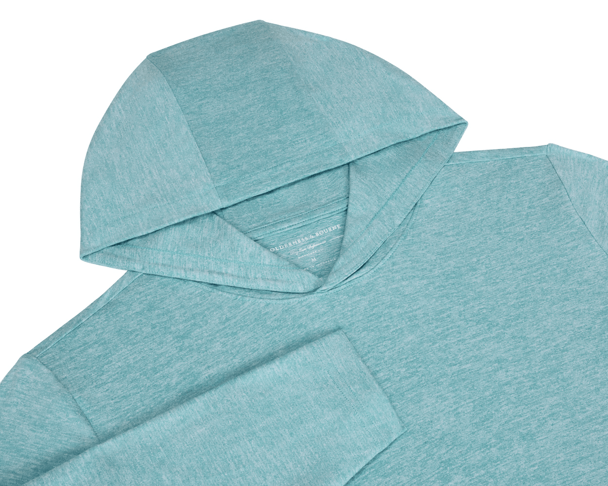 The Stowe Hoodie: Heathered Harbor, featuring a soft, lightweight knit with a hood, sleeve, and athletic drop-tail hem, highlighting Wilderness & Bourne label.