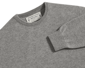 The Buckley Crewneck Sweater: Heathered Gray features a flat-laid light-grey cashmere knit with visible crewneck, shoulder, and sleeve, highlighting the label Holderness & Bourne.