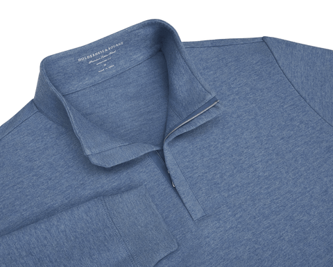 The Harper Quarter-Zip: Heathered Bedford, a blue long-sleeve pullover with a quarter-zip, features a soft cotton-blend knit and ribbed cuffs for comfort.