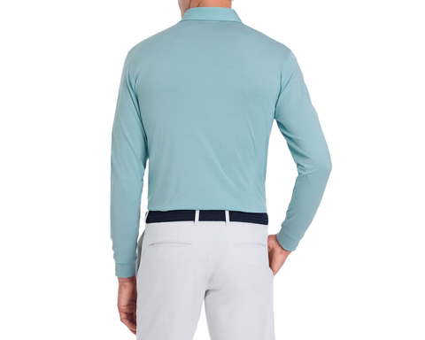 The Burke Shirt: Harbor & White, a light teal-blue long-sleeve polo, worn tucked into trousers with a navy woven belt, showcases style and sun protection.