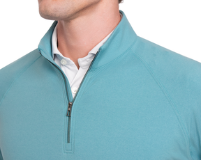 The Westland Quarter-Zip: Heathered Harbor shown over a white collared shirt, features a light teal hue with a partially-open zipper, highlighting its soft, moisture-wicking fabric.