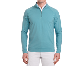 Man wearing The Westland Quarter-Zip: Heathered Harbor, a light teal-blue pullover with gunmetal chrome trim, over a white shirt and beige pants.