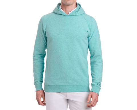 Man wearing The Lawson Hoodie: Heathered Harbor, a plain pullover without drawstrings, layered over a white collared shirt, paired with light-colored pants.