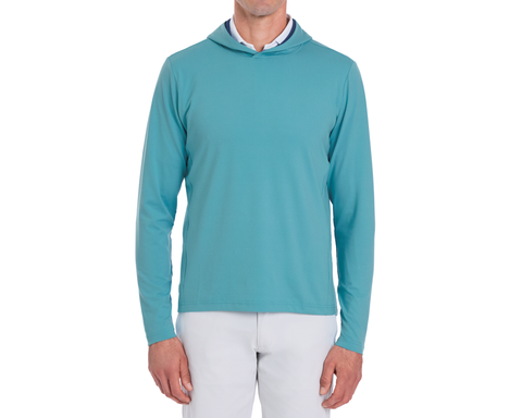 The Jackson Hoodie: Harbor, a lightweight, long-sleeve pullover, styled over a white shirt with light grey pants, perfect for versatile golf layering.