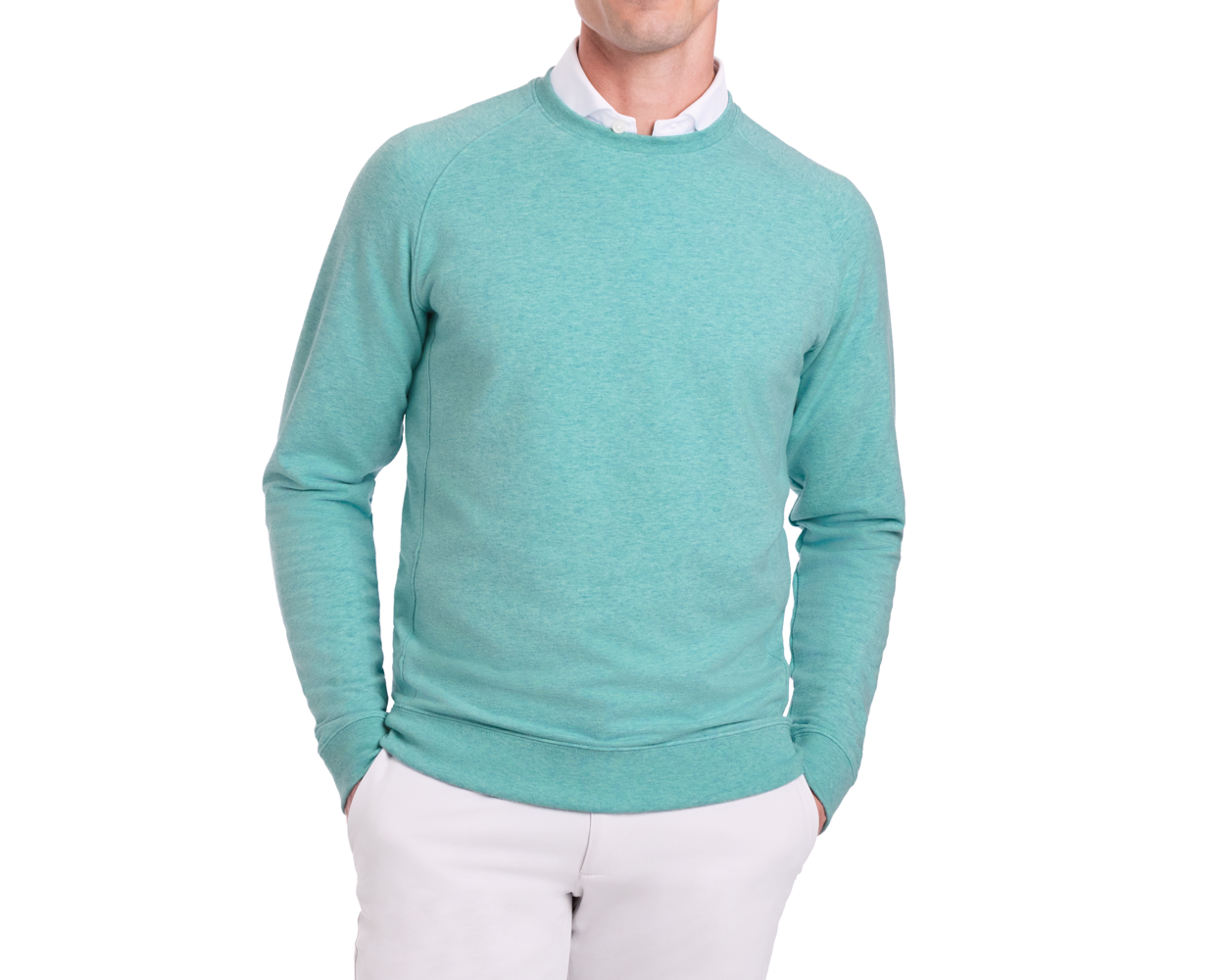Person wearing The Kennedy Crewneck: Heathered Harbor over a white collared shirt, showcasing its comfortable cotton blend and plush terry interior. Hands in light-colored pants pockets.