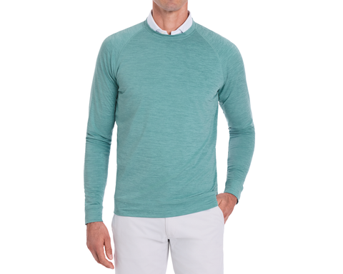 Person wearing The Laidlay Crewneck: Heathered Harbor over a white collared shirt, paired with light trousers, showcasing its soft, stretchy fit and heathered texture.