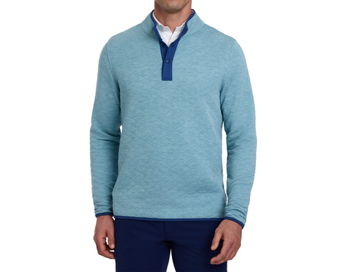 Man wearing The Sullivan Quarter-Snap: Heathered Harbor, showcasing its quilted texture, contrasting snap-placket, and collar lining, over a white shirt with dark trousers.