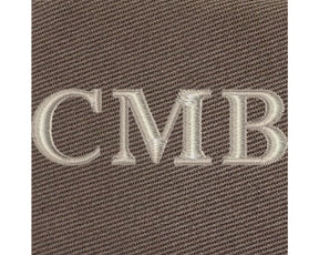 The Travis Tote Bag features cream-white CMB embroidery on brown woven fabric, showcasing personalized initials on its durable cotton twill design.