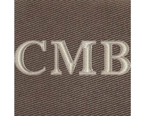 The Travis Tote Bag features cream-white CMB embroidery on brown woven fabric, showcasing personalized initials on its durable cotton twill design.