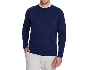 Man wearing The Laidlay Crewneck: Heathered Navy, featuring a heathered texture, over a white shirt, paired with light trousers, hand casually in pocket.