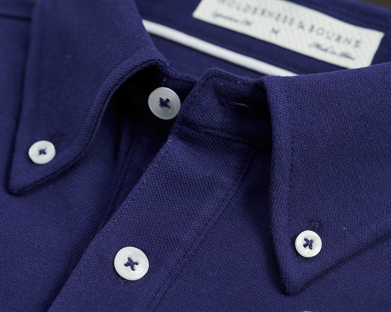 The Burton Shirt: Navy, featuring a detailed close-up of the button-down collar with visible white buttons and textured pique knit fabric.