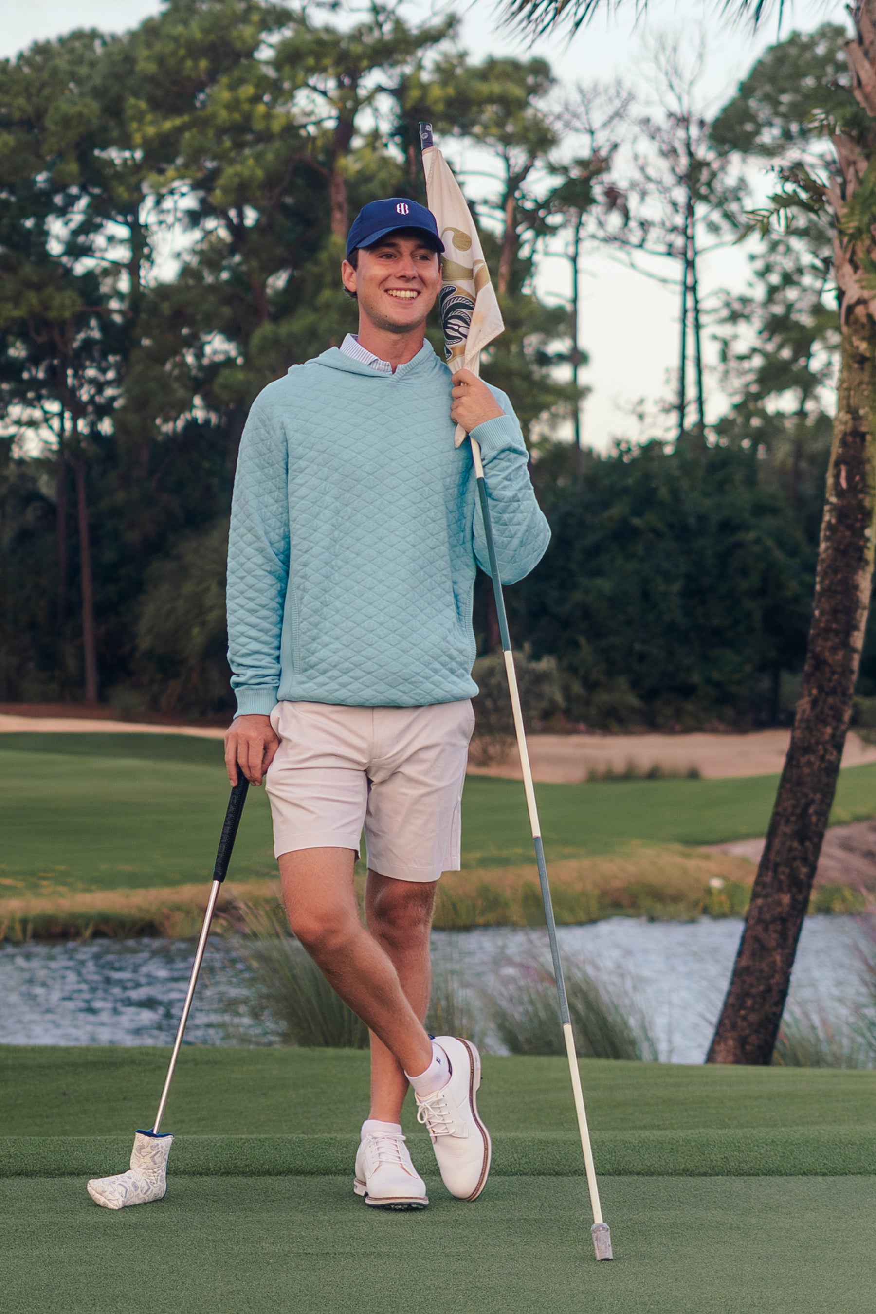 Man on a golf course holding a golf club with a scenic background