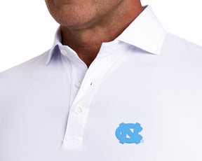 Detail of University of North Carolina Anderson Shirt: White on a model, showing the open collar, placket buttons, and light blue interlocking NC embroidery.