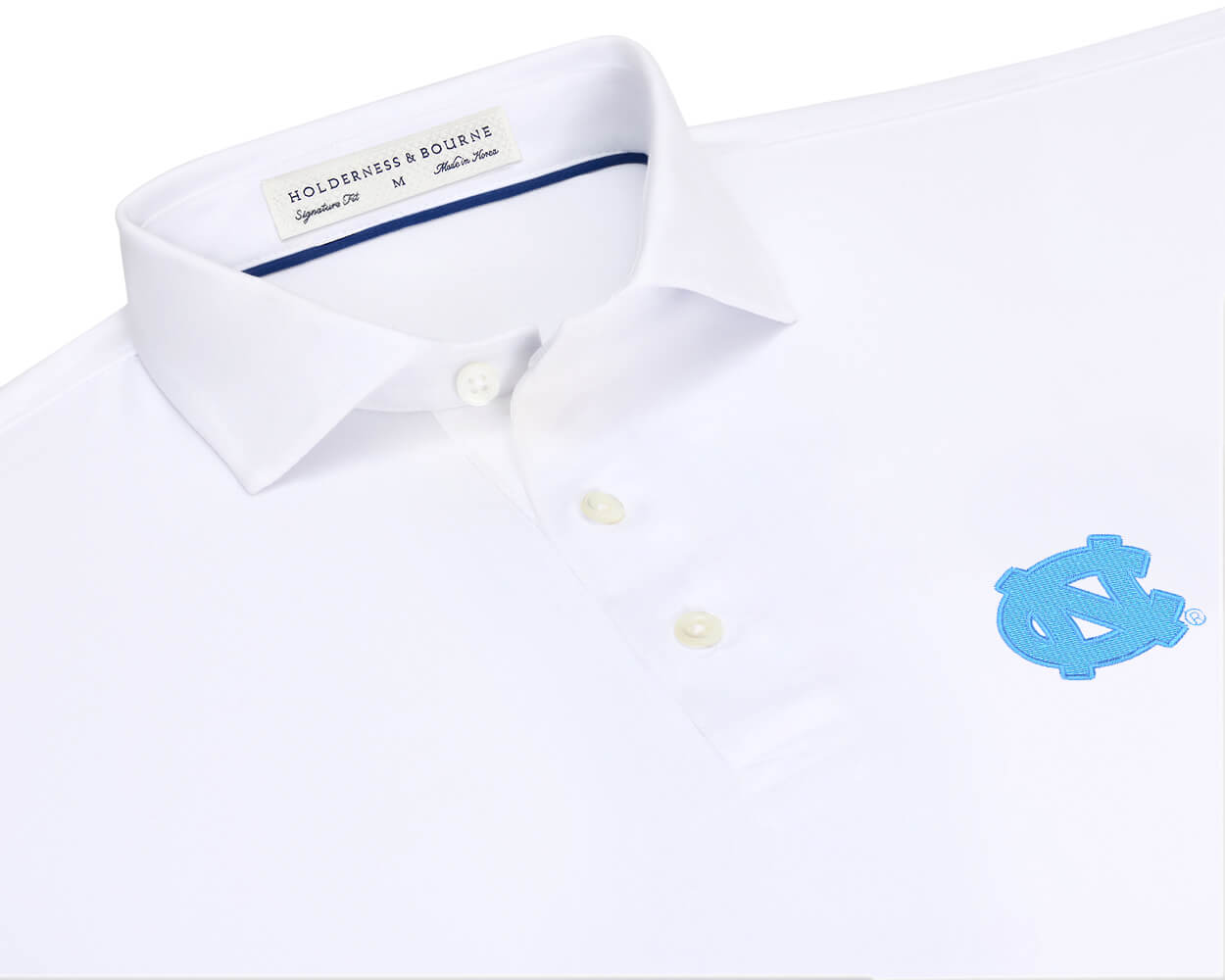 Close-up of University of North Carolina Anderson Shirt: White showing the spread collar, three buttons, navy collar piping, and light blue interlocking NC embroidery.