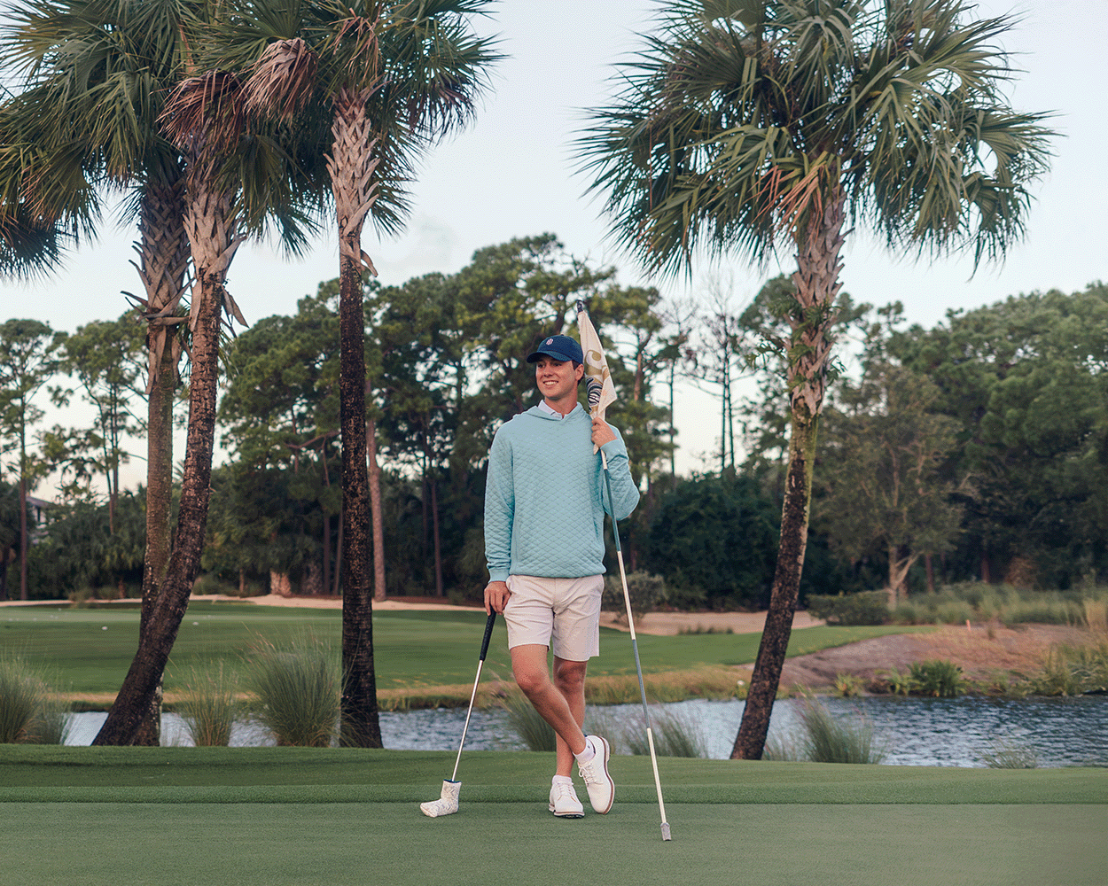 The Wallace Hoodie Sweater: Heathered Harbor on a golfer, featuring a quilted design, ribbed panels, and a relaxed fit, perfect for cool weather.