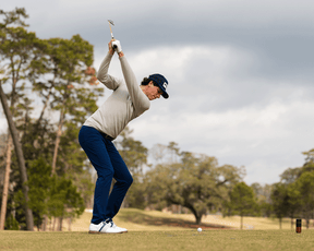 Golfer in mid-backswing wearing The Westland Quarter-Zip: Heathered Dune, showcasing its lightweight, moisture-wicking fabric and versatile design for on and off the course.