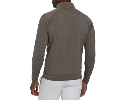 Back view of a model wearing The Westland Quarter-Zip: Heathered Driftwood, showing raglan sleeves, ribbed hem, and a small upper-back logo with light gray pants.