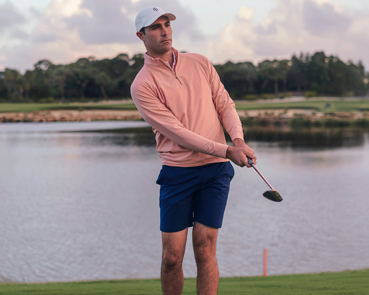 Man golfing by lake wearing The Westland Quarter-Zip: Heathered Nectarine, showcasing its lightweight, moisture-wicking fabric and versatile design for on and off-course comfort.