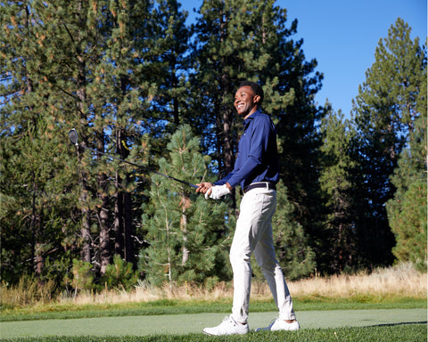 Man on golf course wearing The Farrell Shirt: Navy, holding a driver, showcasing its long sleeves, spread collar, and comfort features ideal for various weather conditions.